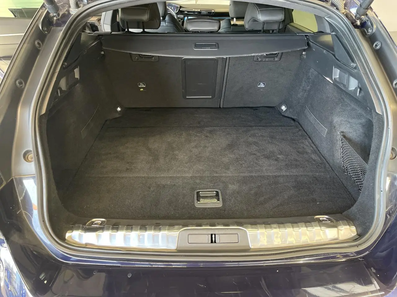 Coffre ouvert d'un break Peugeot 508 SW bleu foncé, montrant un espace de chargement propre et bien fini.