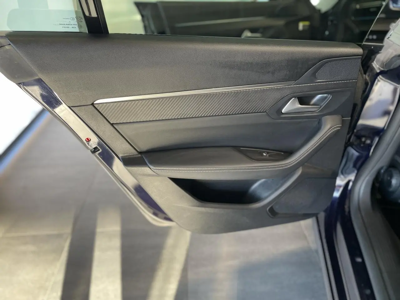 Vue rapprochée de la porte arrière gauche bleu foncé du Peugeot 508 SW avec garniture noire et insert carbone.