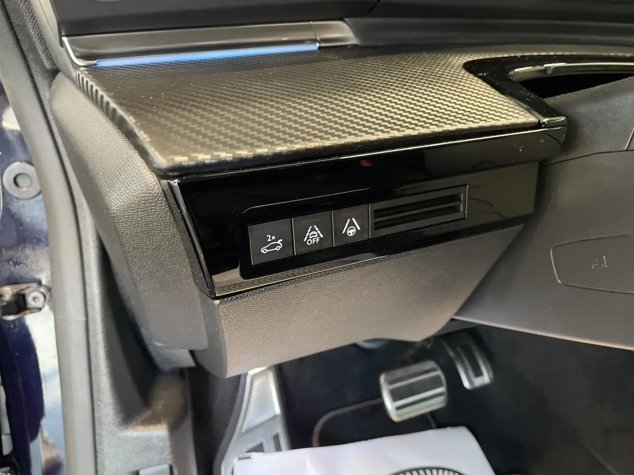 Vue rapprochée des commandes sous le tableau de bord côté gauche d'une Peugeot 508 SW bleu foncé.