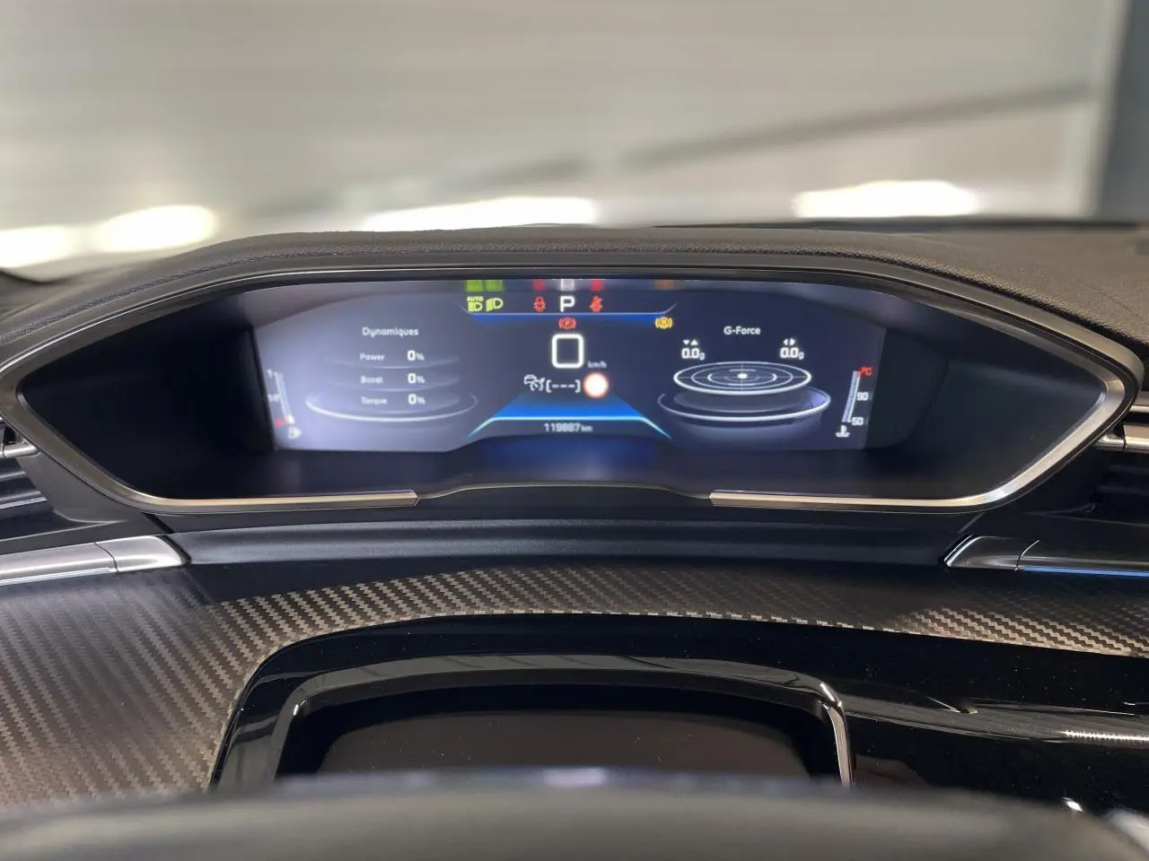 Tableau de bord numérique de Peugeot 508 SW 2021 vu de face, avec affichage des données de conduite et finition carbone.