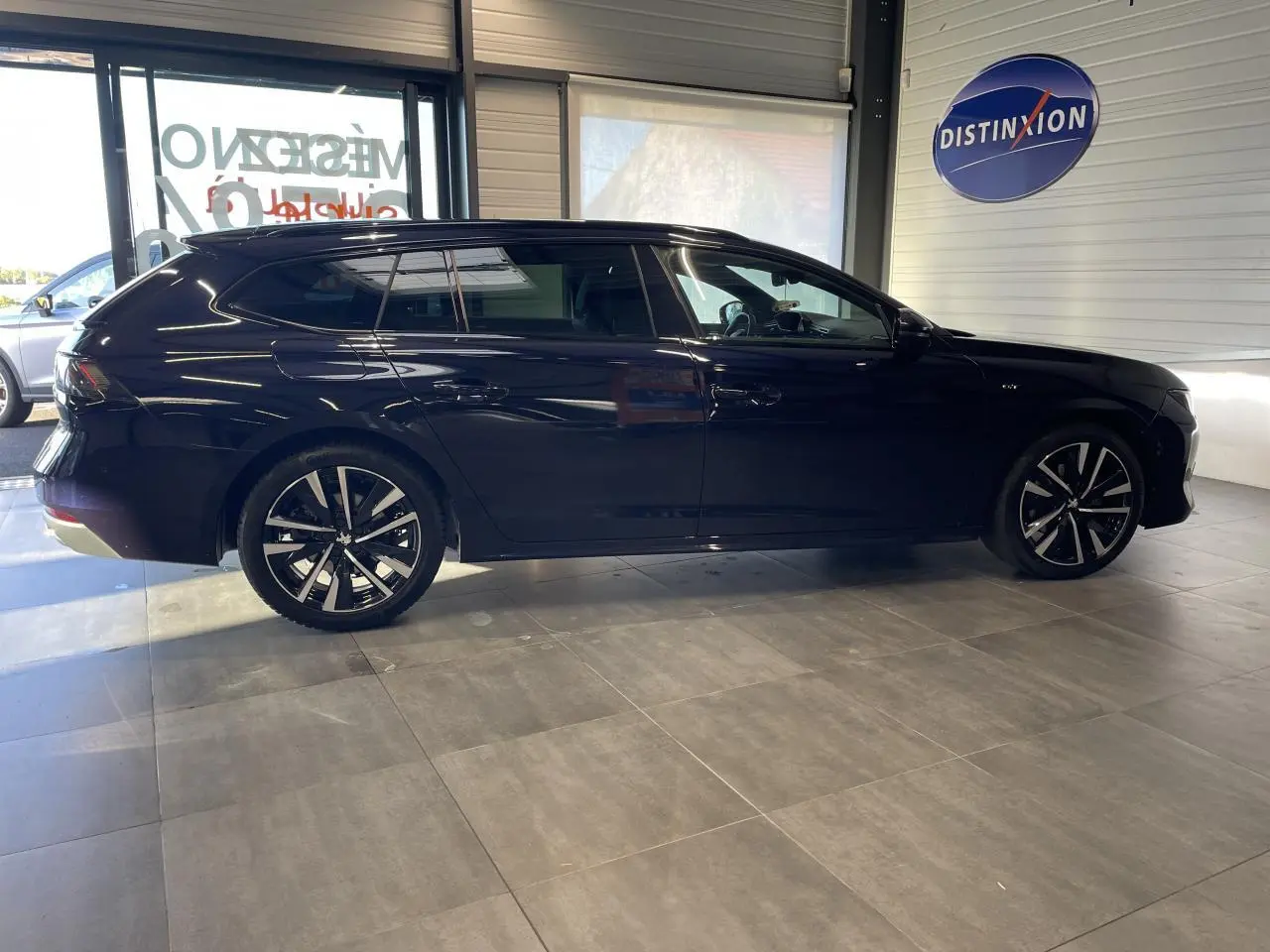 Peugeot 508 SW bleu foncé vue de profil côté gauche en intérieur avec jantes alliage noires et diamantées.