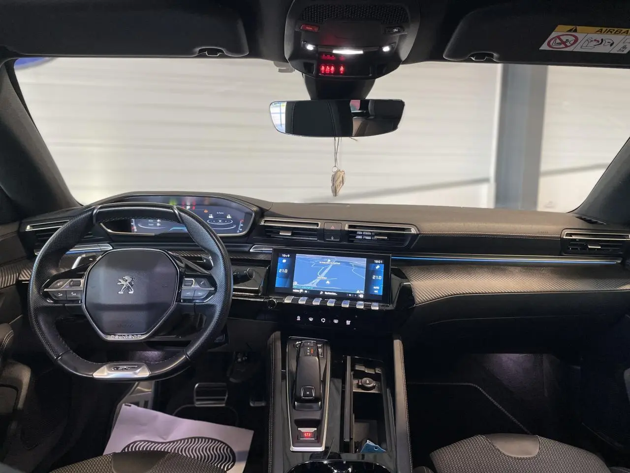 Vue intérieure avant du Peugeot 508 SW 2021 avec tableau de bord noir, écran tactile et volant compact au logo lion.