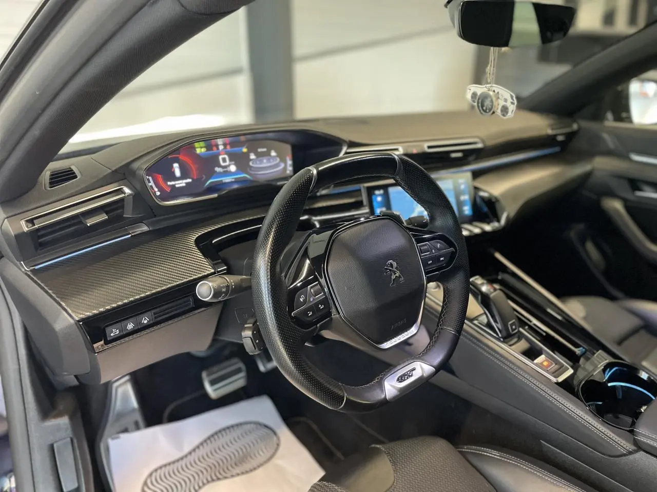 Vue intérieure côté conducteur du Peugeot 508 SW 2021, tableau de bord moderne avec volant compact et écran numérique couleur.