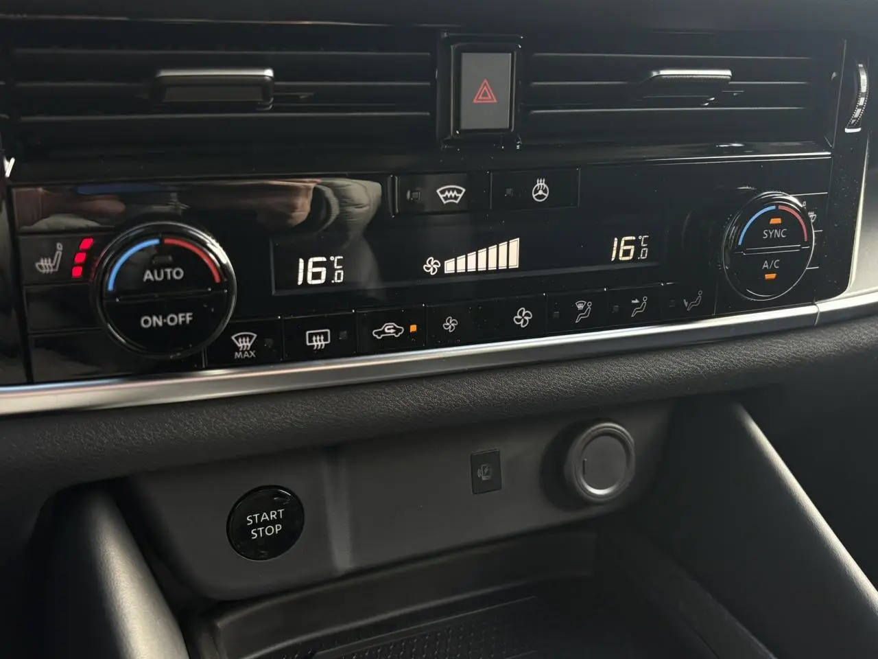 Gros plan sur la console centrale du Nissan Qashqai 2025, affichage numérique de la climatisation à 16°C et bouton Start/Stop.