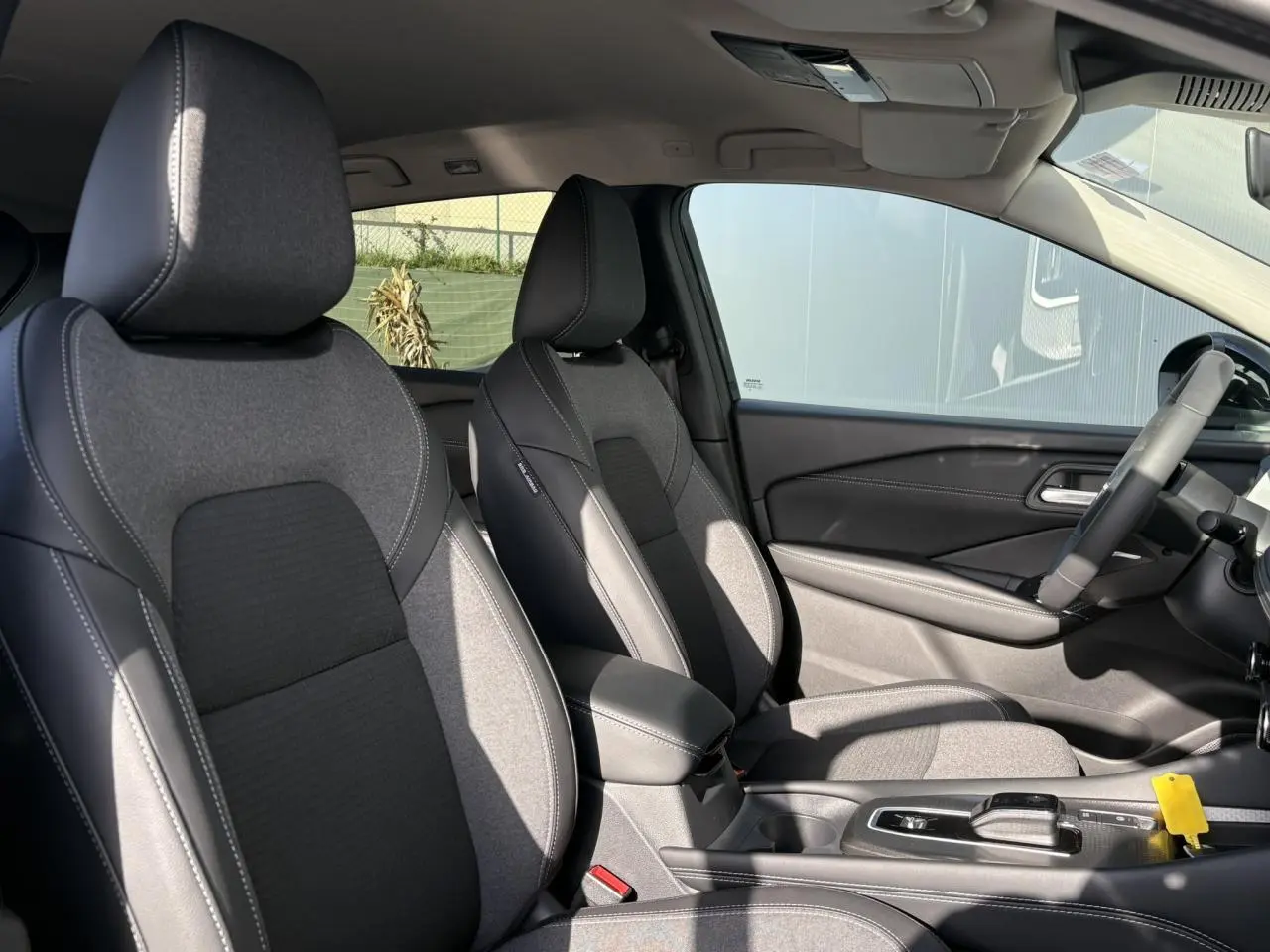Vue intérieure côté droit montrant les sièges avant gris et noir du Nissan Qashqai III e-Power avec console centrale et volant.
