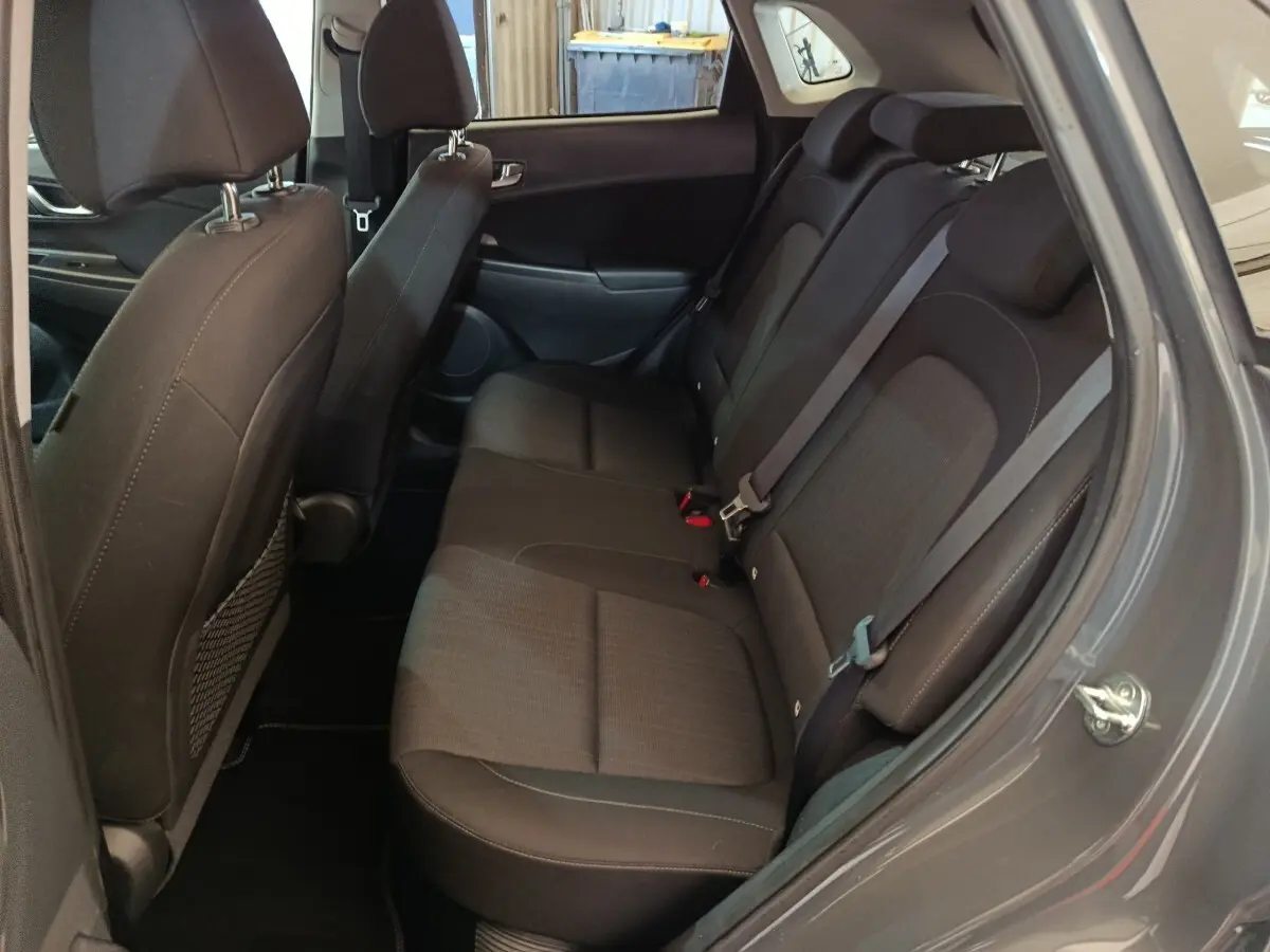 Vue côté droit de la banquette arrière noire du Hyundai Kona 1.6 Hybrid 2023, avec ceintures de sécurité visibles.