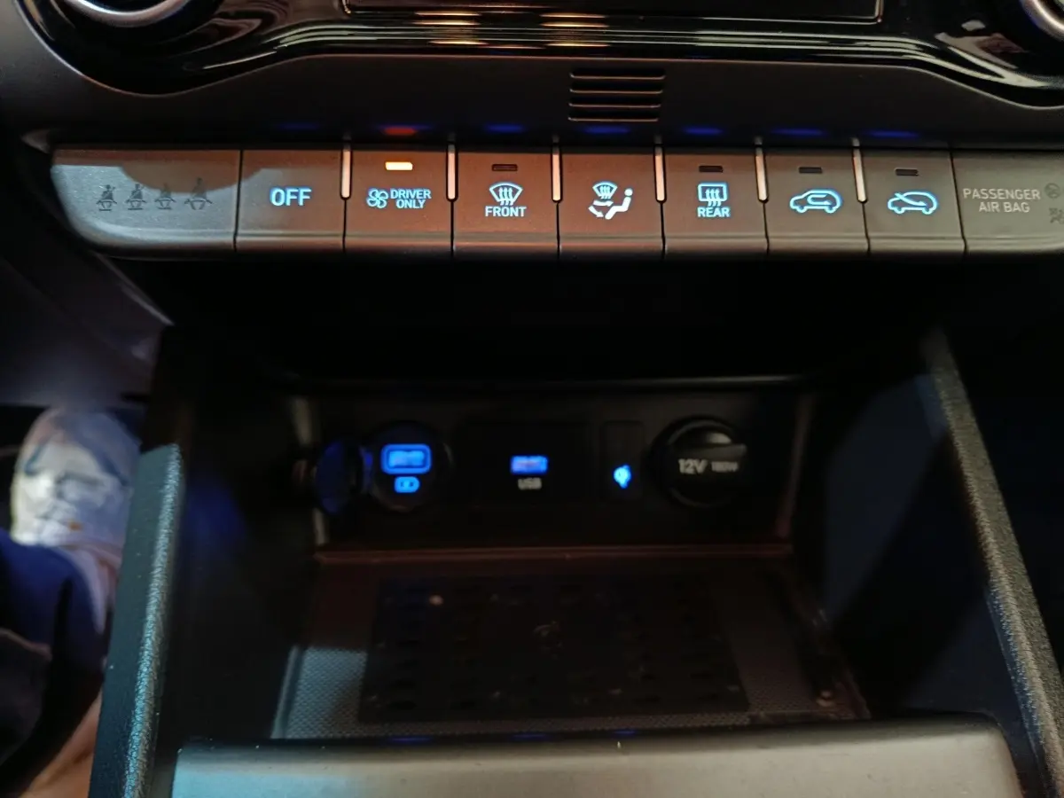 Vue rapprochée du tableau de bord central du Hyundai Kona 2023, montrant les commandes climatisation et prises USB éclairées.