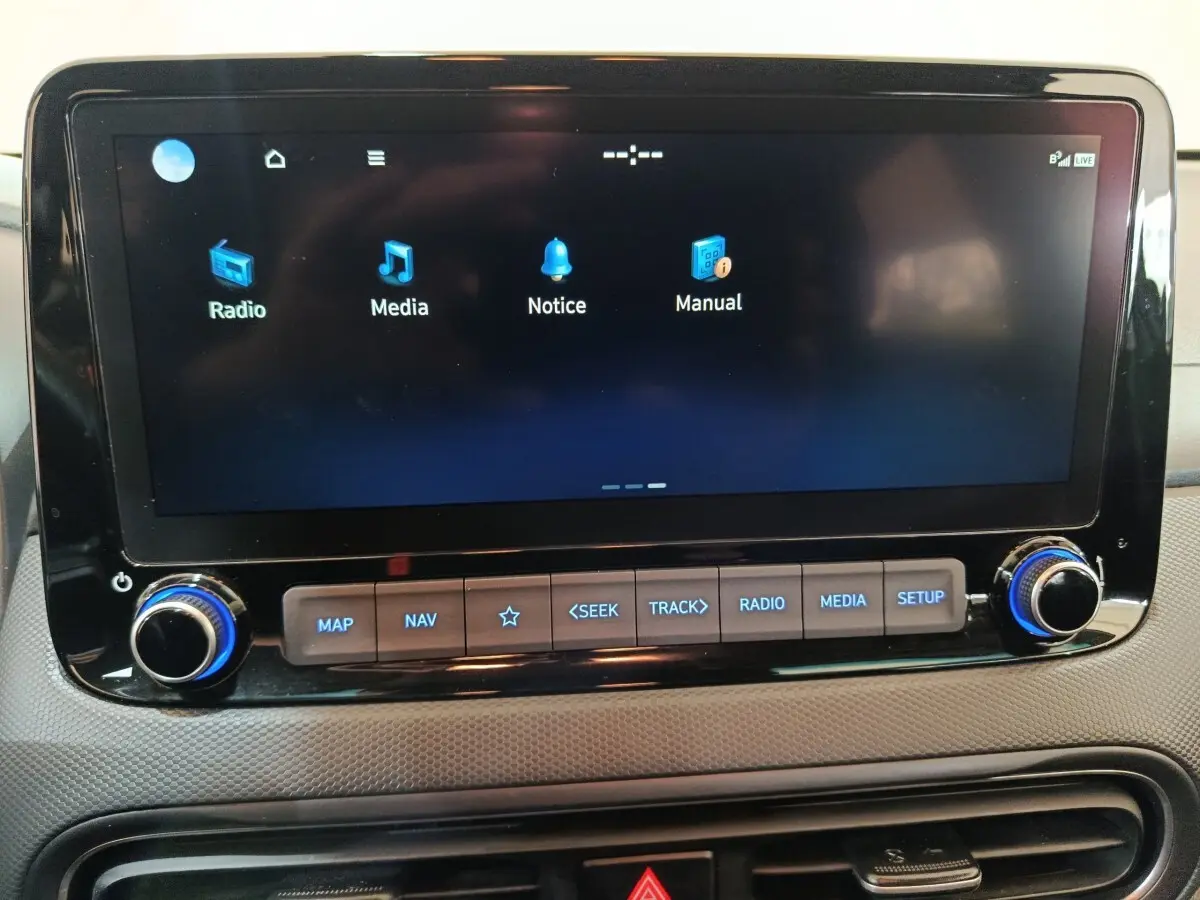 Écran tactile central du tableau de bord de la Hyundai Kona gris foncé, avec commandes multimédia rétroéclairées en bleu.