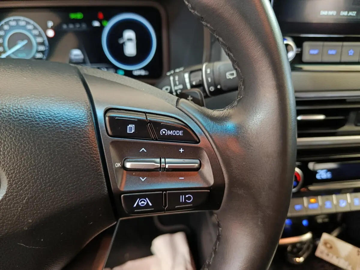 Gros plan sur le volant cuir multifonctions du Hyundai Kona 2023, avec commandes de régulateur et affichage numérique en arrière-plan.