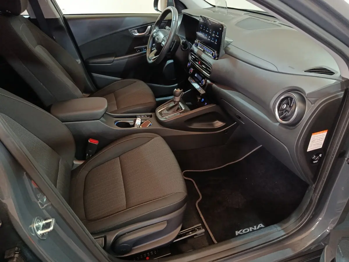 Vue intérieure côté conducteur du Hyundai Kona gris foncé 2023, avec volant cuir multifonctions et écran tactile central.