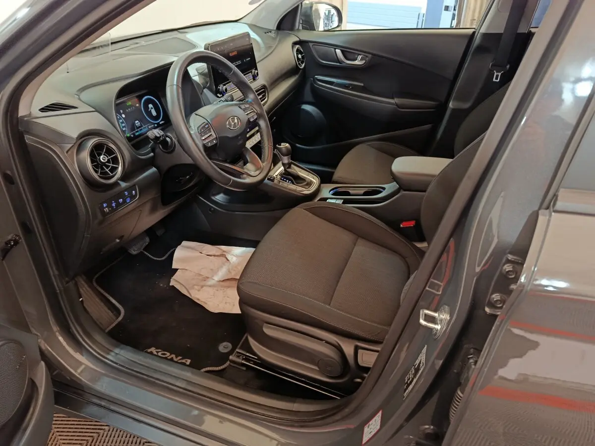 Vue intérieure côté conducteur du Hyundai Kona gris foncé 2023, volant cuir multifonctions et tableau de bord numérique.