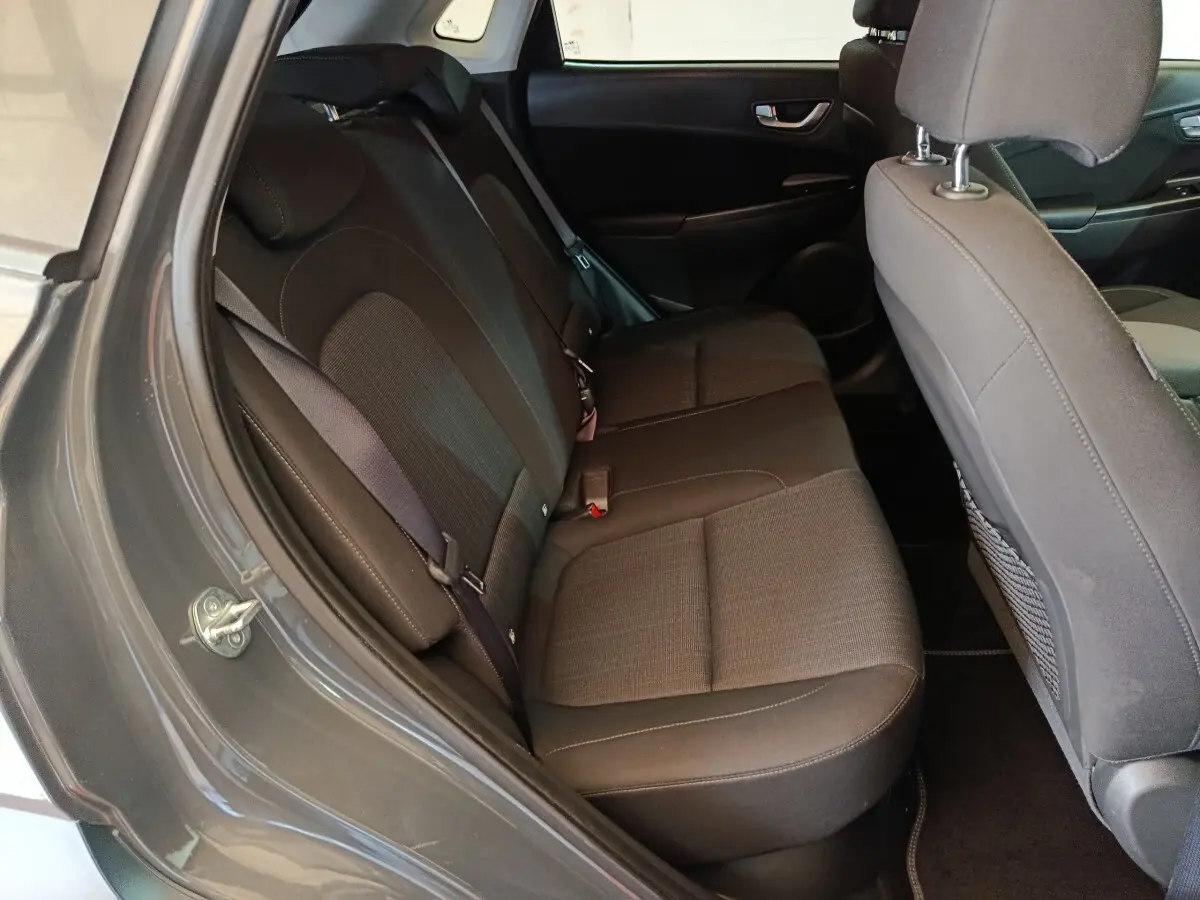 Vue intérieure côté gauche montrant la banquette arrière gris foncé du Hyundai Kona 1.6 Hybrid 2023.