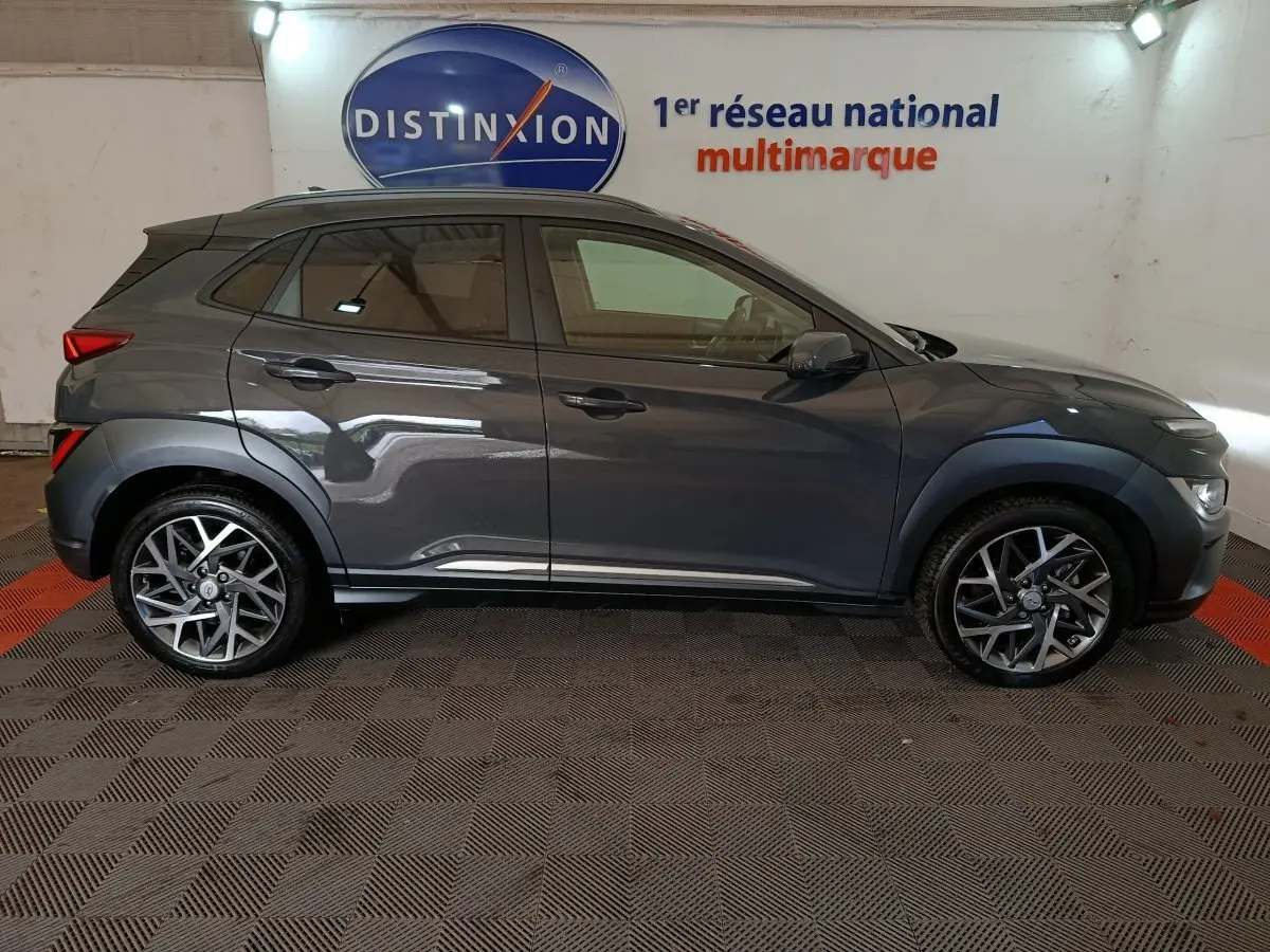 Profil droit d'un Hyundai Kona gris foncé 2023, avec jantes alliage et protections noires sur les passages de roues.