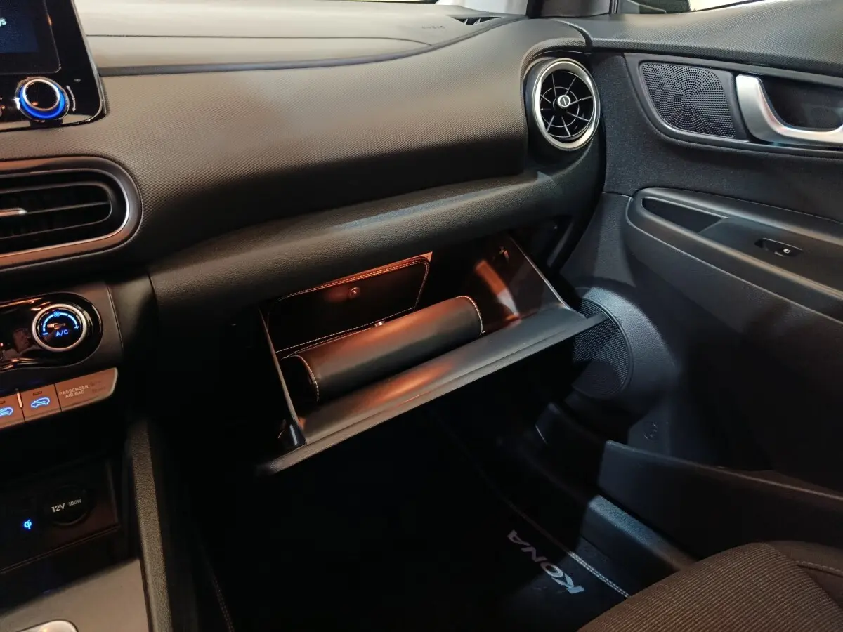 Vue intérieure côté passager du tableau de bord gris foncé du Hyundai Kona 2023 avec boîte à gants ouverte.
