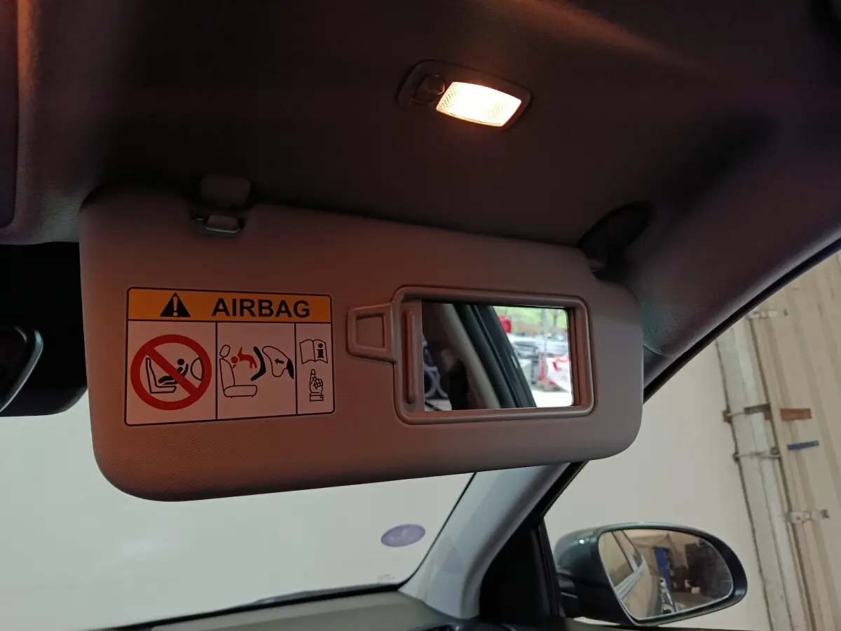 Vue intérieure du pare-soleil côté conducteur avec miroir et avertissement airbag dans un Hyundai Kona gris foncé 2023.
