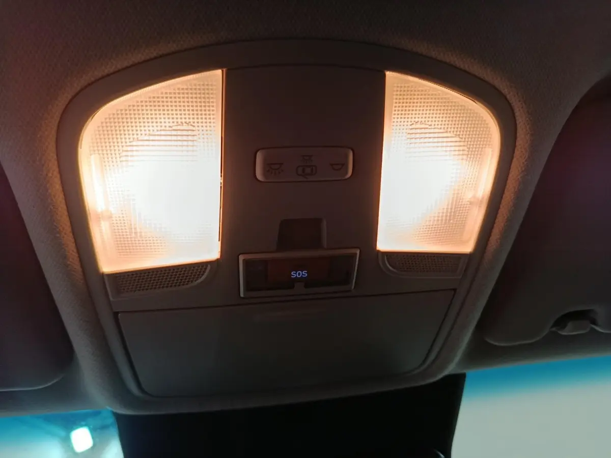 Plafonnier intérieur allumé avec bouton SOS visible dans une Hyundai Kona gris foncé, vue du plafond avant.