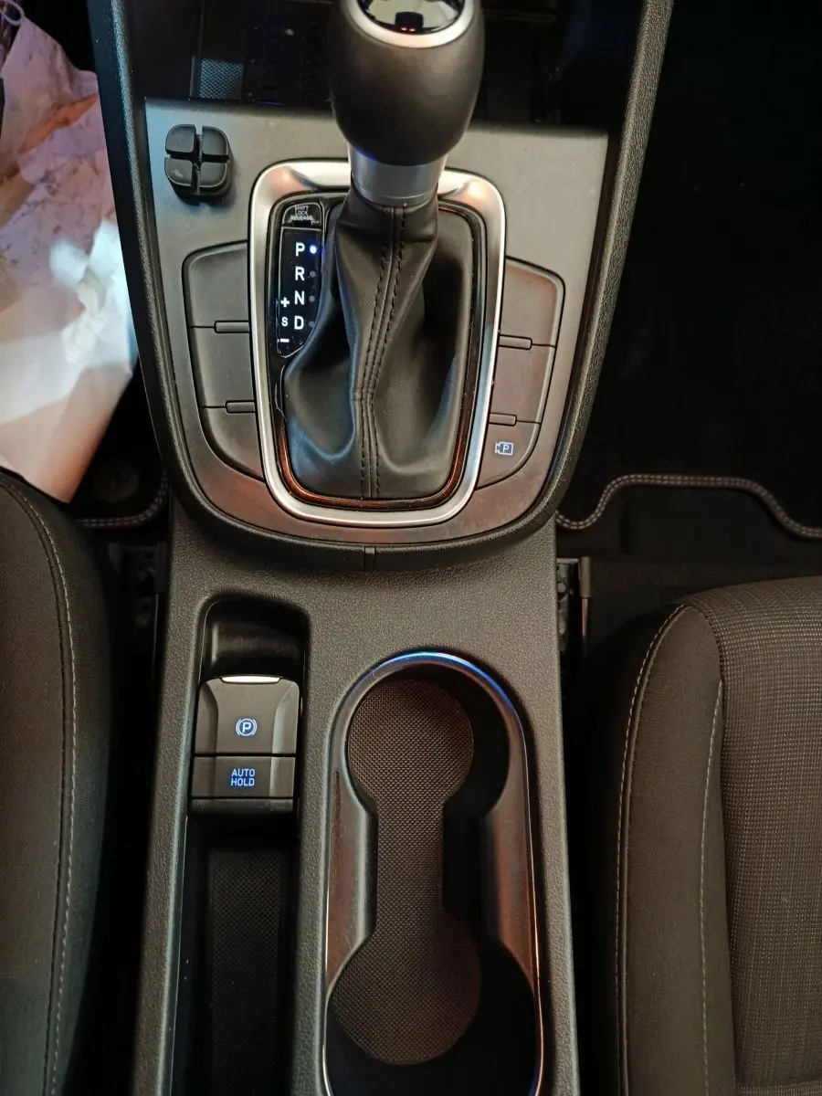 Vue plongeante sur la console centrale noire du Hyundai Kona 2023 avec levier de vitesse automatique et porte-gobelets.