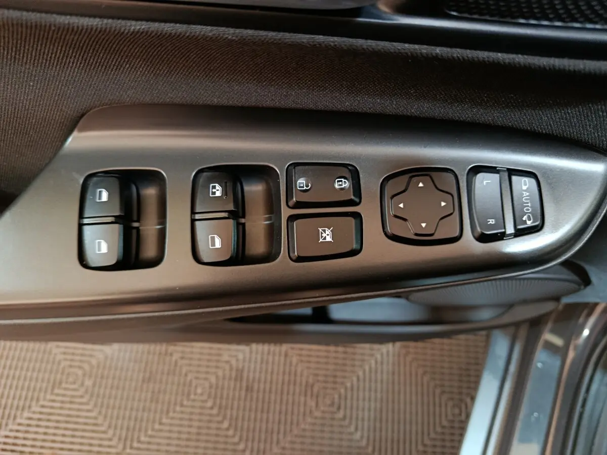 Vue rapprochée des commandes de lève-vitres et rétroviseurs sur la porte côté conducteur d’un Hyundai Kona gris foncé 2023.