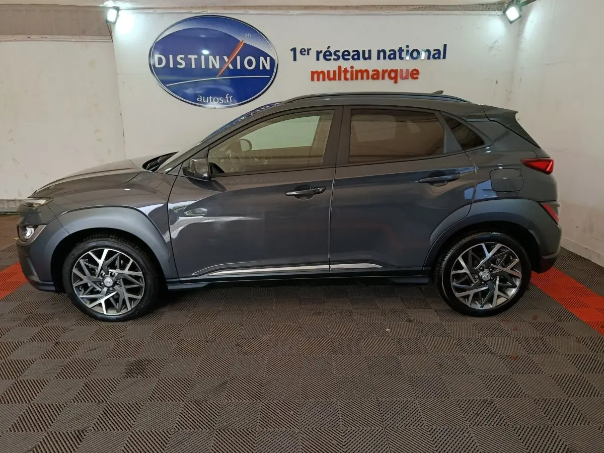 Vue de profil côté gauche d'un Hyundai Kona 1.6 Hybrid 141 Creative gris foncé avec jantes alliage et toit noir.