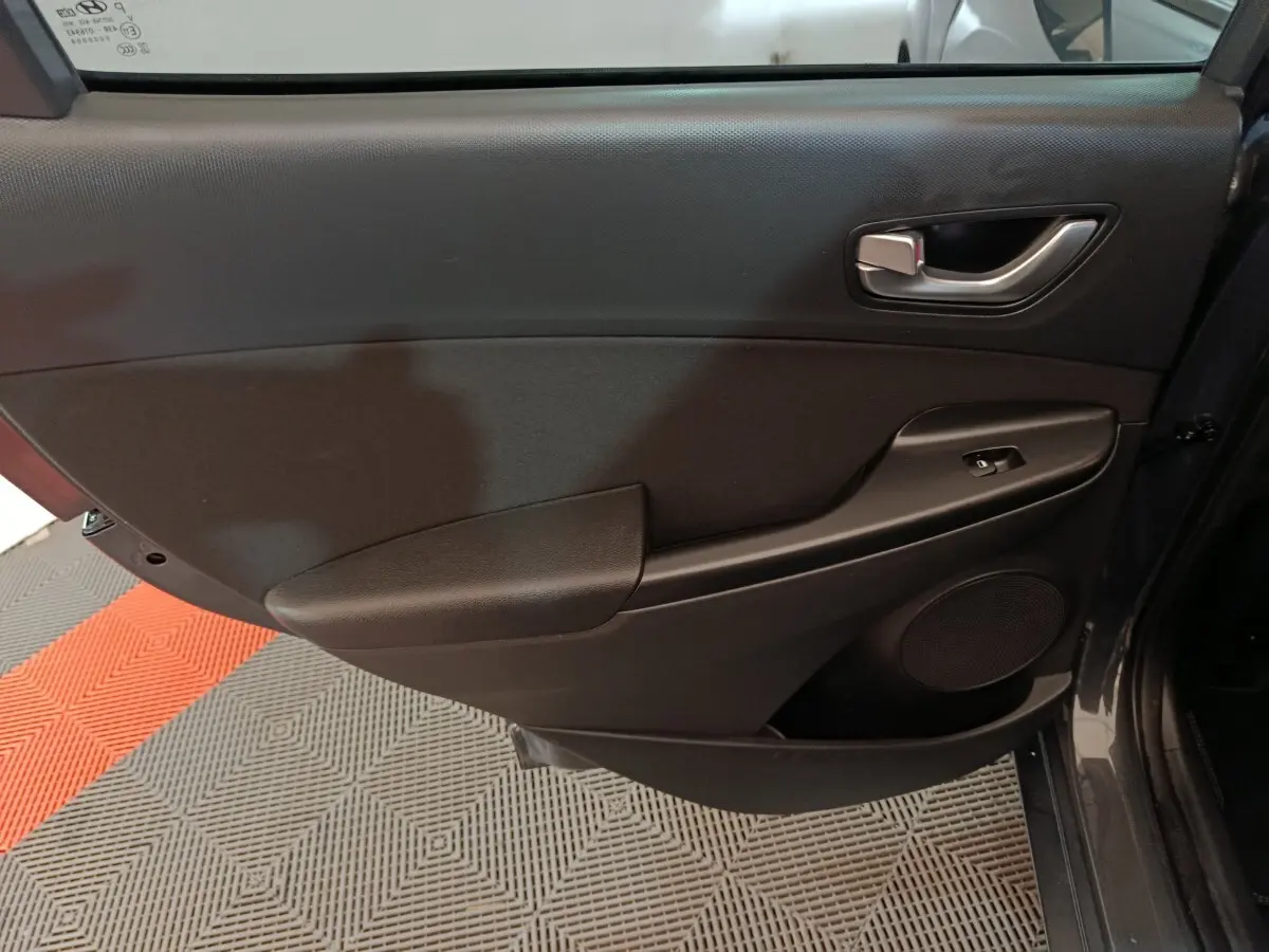 Vue rapprochée de la porte arrière droite gris foncé du Hyundai Kona 1.6 Hybrid 2023 avec poignée et commande de vitre.