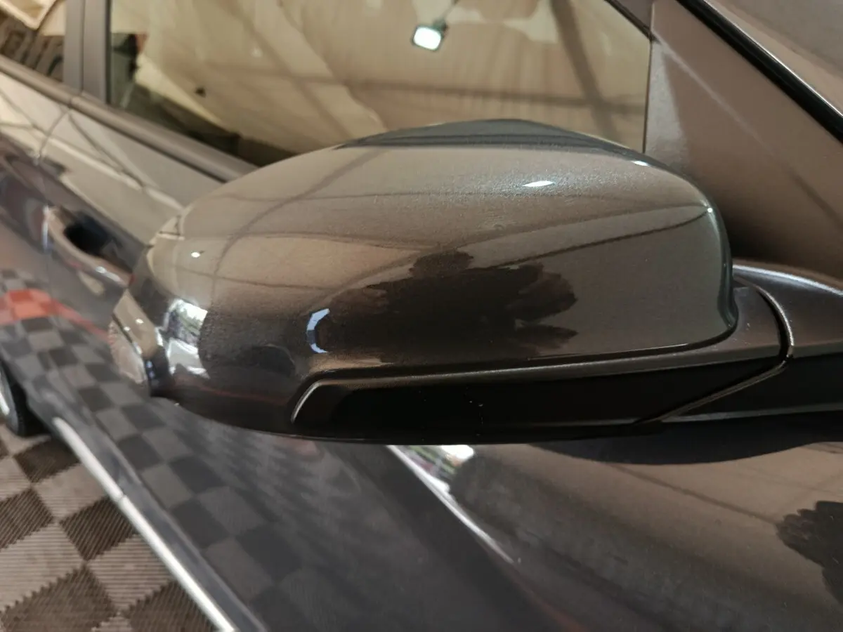 Gros plan sur le rétroviseur droit gris foncé du Hyundai Kona 1.6 Hybrid 2023, avec reflet de l'environnement intérieur.