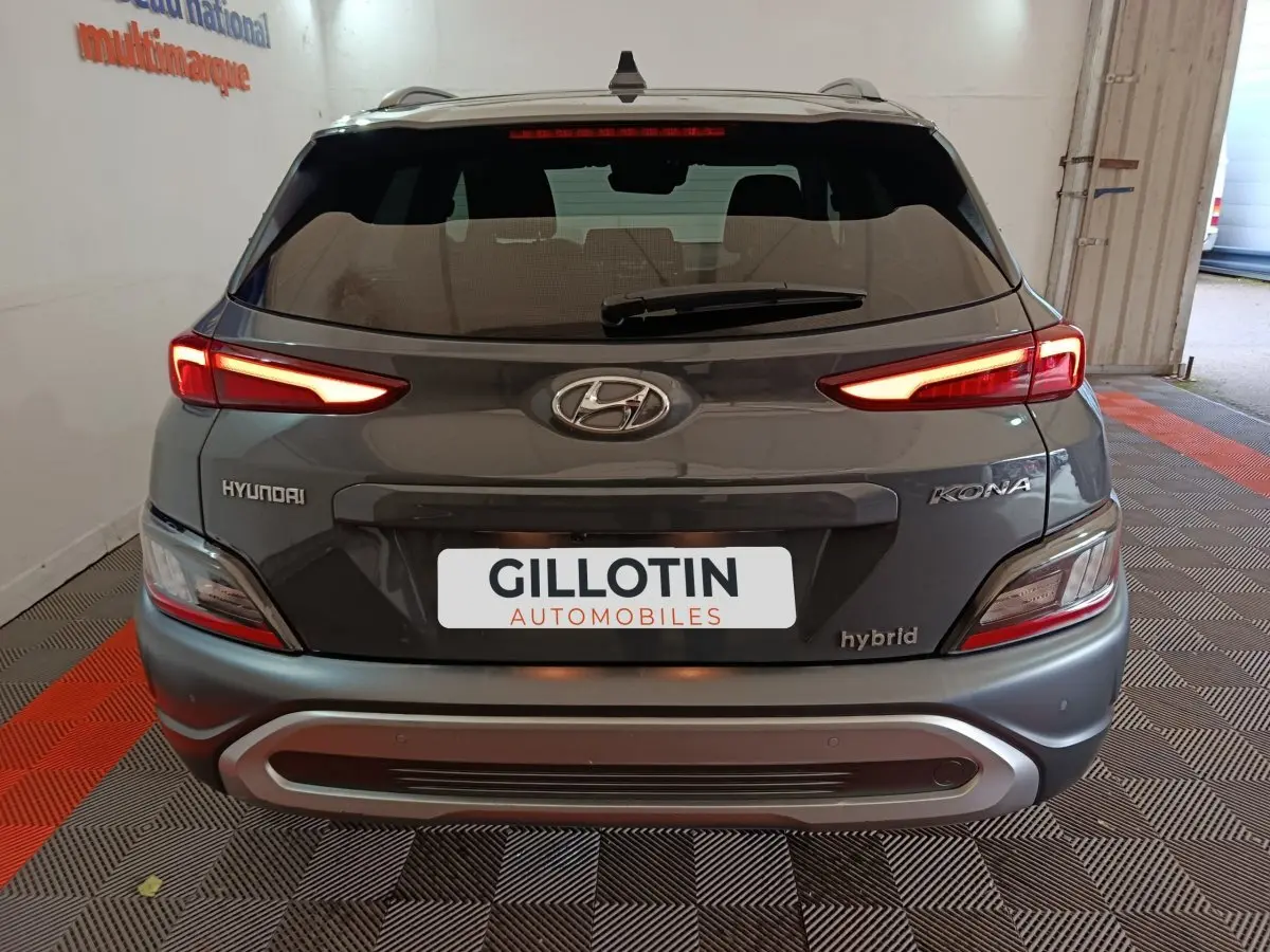 Vue arrière d’un Hyundai Kona gris foncé hybride 2023 avec feux LED allumés et logo Hyundai visible.