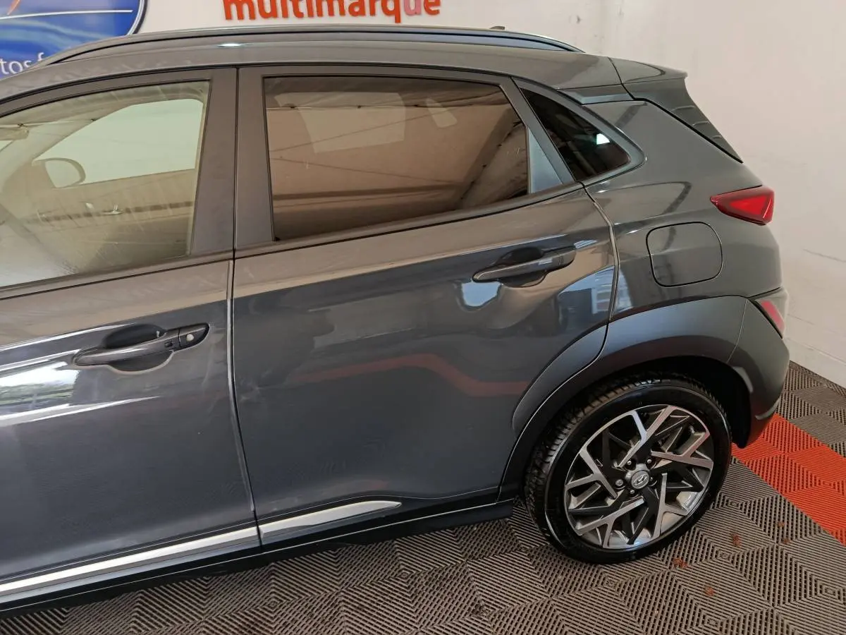 Vue latérale droite sur la partie arrière d’un Hyundai Kona gris foncé avec jante alliage et poignées de porte noires.