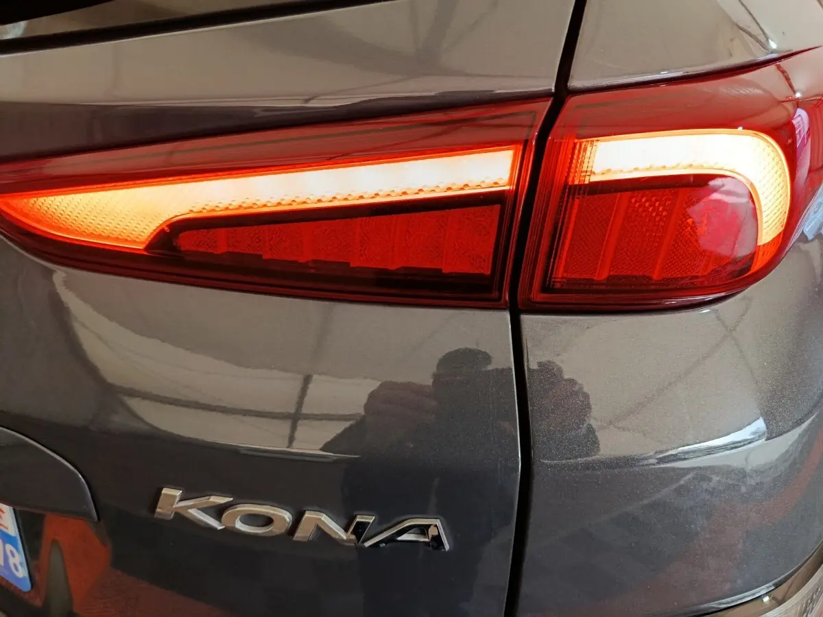 Gros plan sur le feu arrière droit rouge allumé d’un Hyundai Kona gris foncé avec logo visible sur la carrosserie.