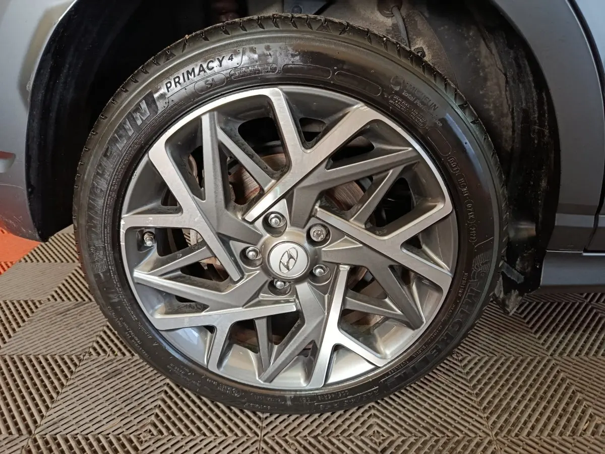 Gros plan sur la jante alliage grise au design géométrique du Hyundai Kona gris foncé, roue avant droite visible.