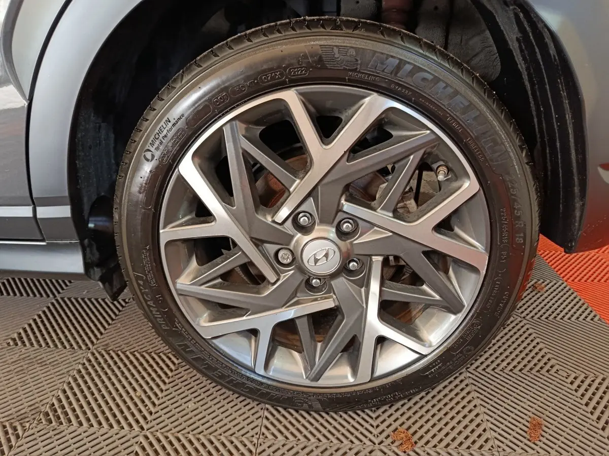 Gros plan sur la roue avant droite de la Hyundai Kona gris foncé, mettant en valeur la jante alliage au design géométrique.