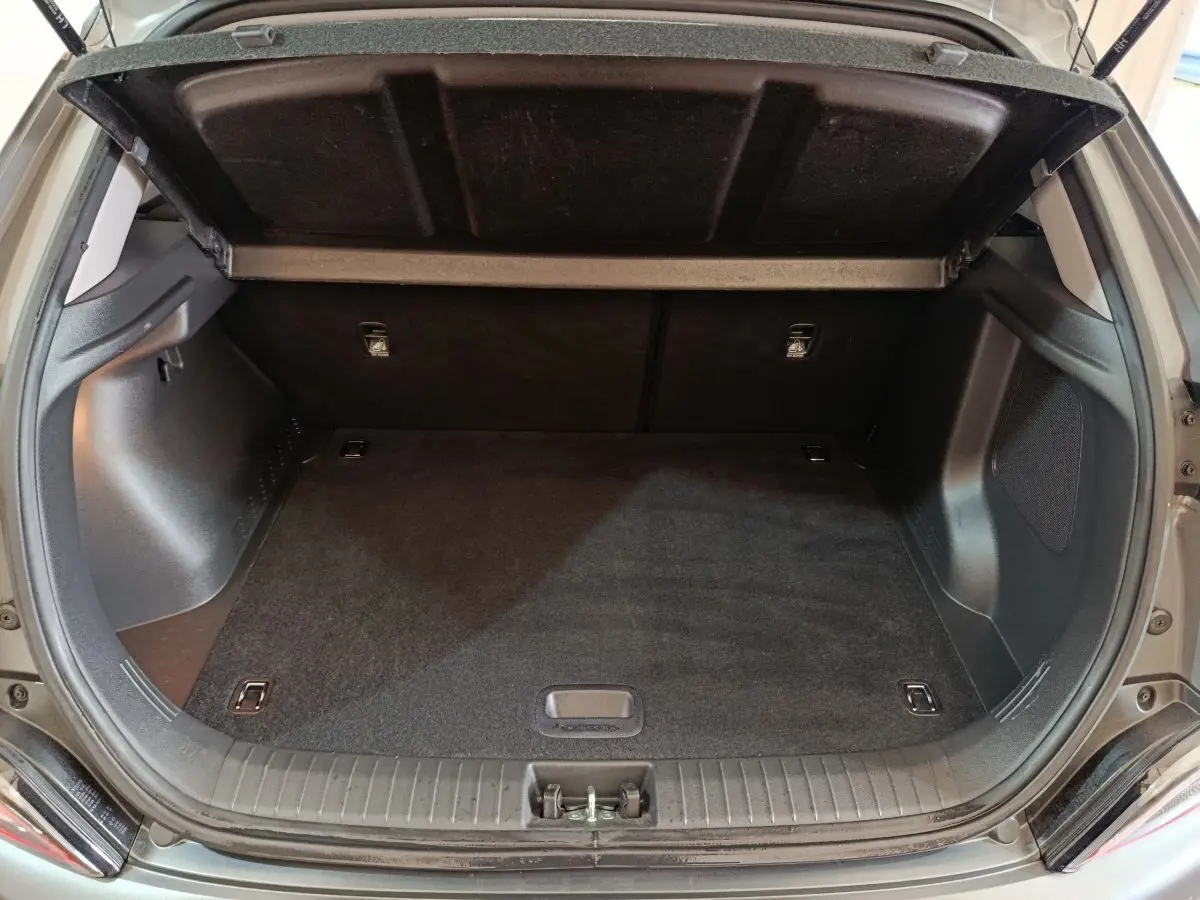 Coffre ouvert vu de l'arrière d'un Hyundai Kona gris foncé, espace de chargement propre et vide.