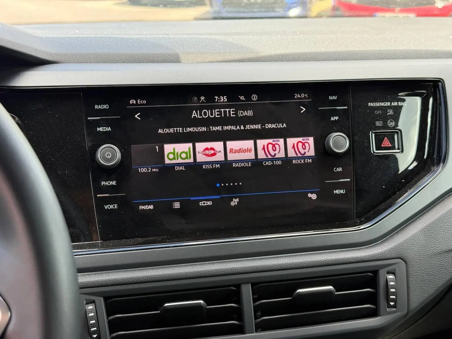 Vue rapprochée de l'écran tactile central noir du Volkswagen Taigo gris, affichant les stations radio numériques.