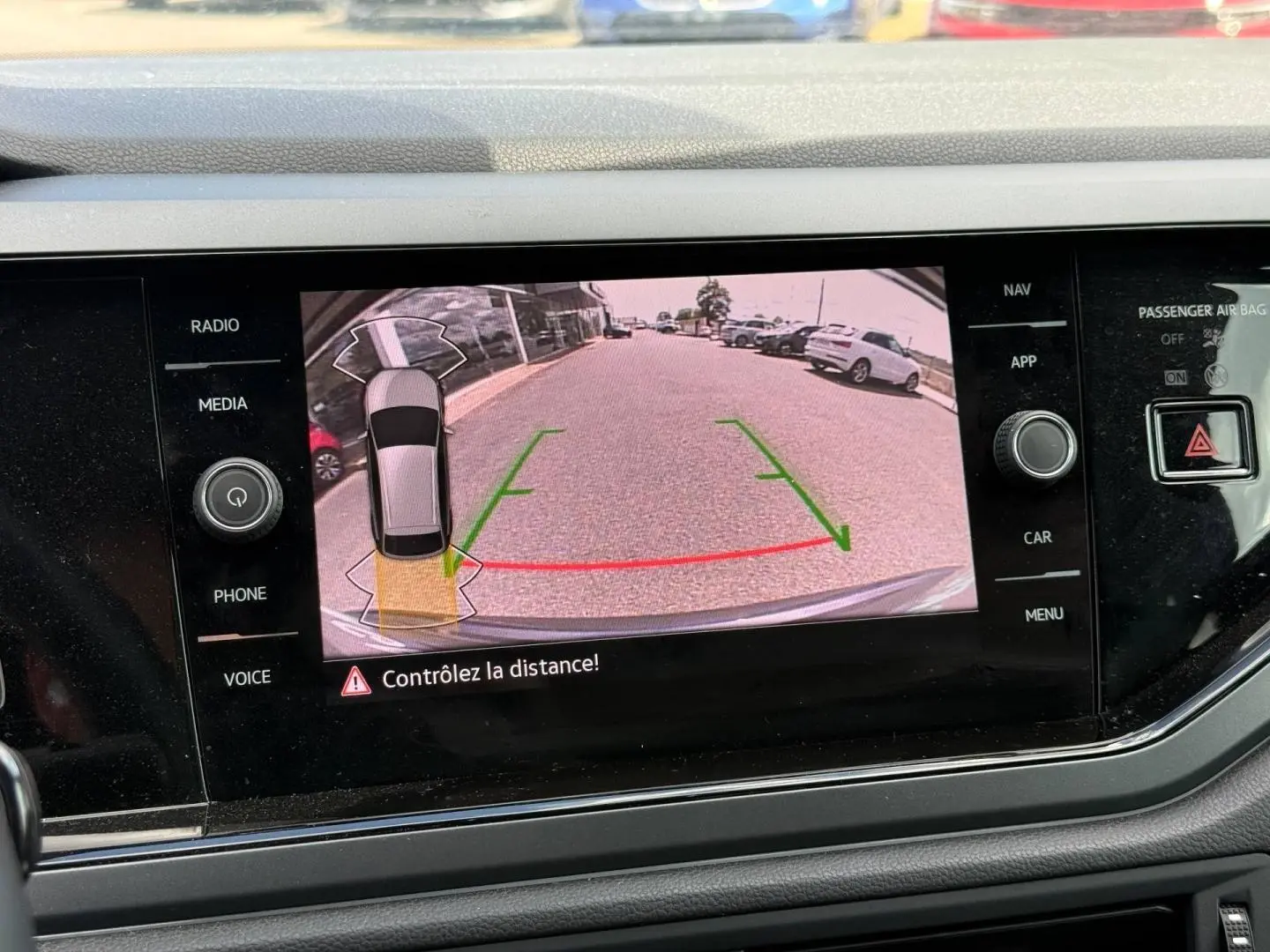 Vue de l'écran tactile montrant la caméra de recul active du Volkswagen Taigo gris, avec lignes de guidage vertes et rouges.