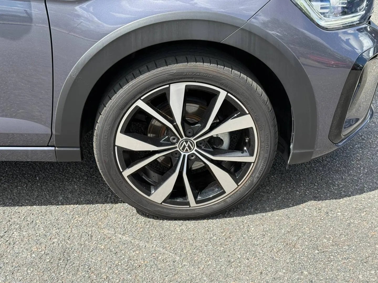 Gros plan sur la roue avant droite avec jante alliage bicolore du Volkswagen Taigo gris Ascot 2025.