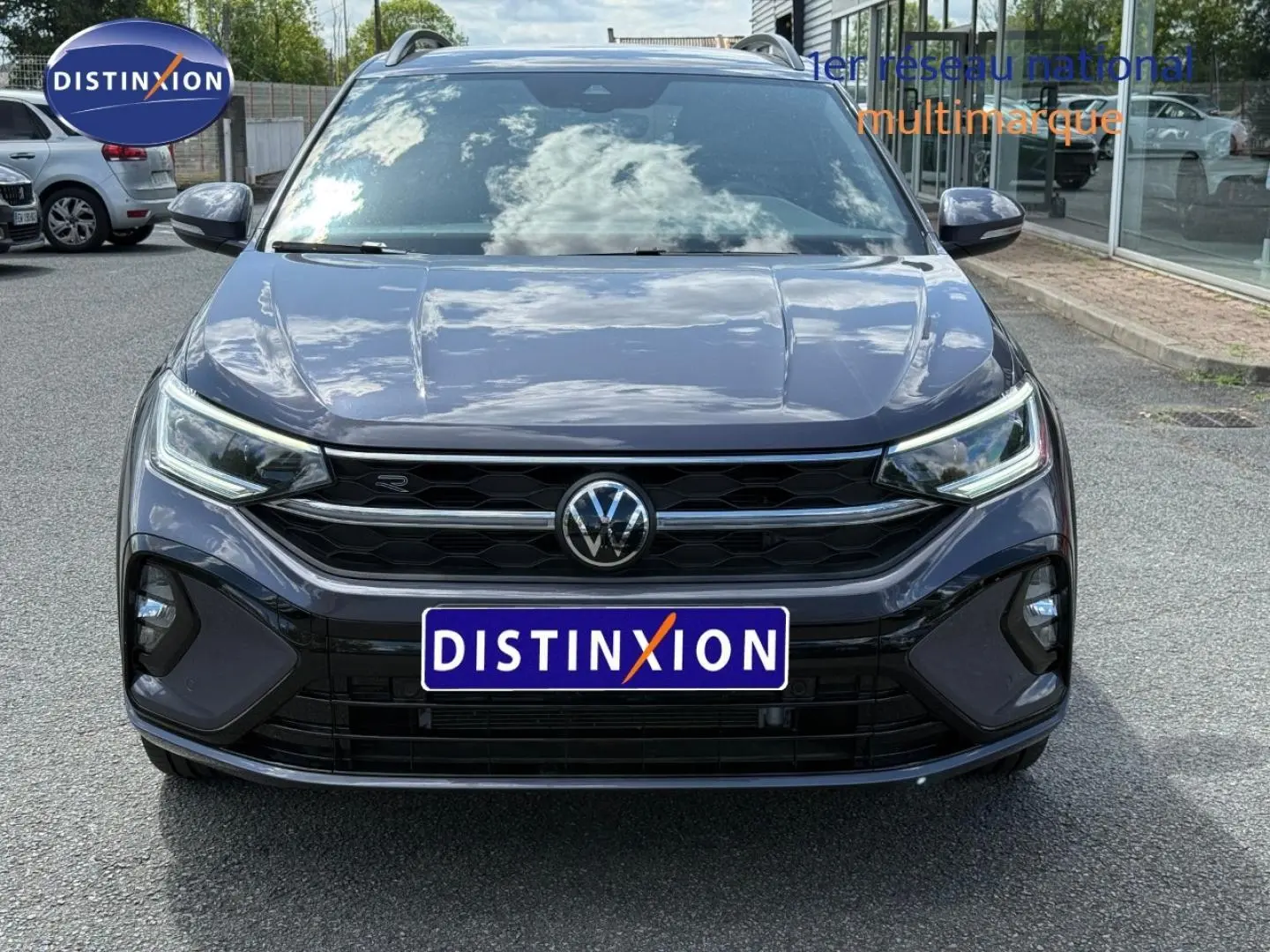Vue avant d'un Volkswagen Taigo gris Ascot 2025 avec calandre noire et phares LED allumés.