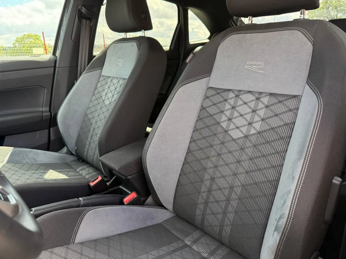 Gros plan sur les sièges avant gris R-Line avec surpiqûres et logo "R" du Volkswagen Taigo 2025.