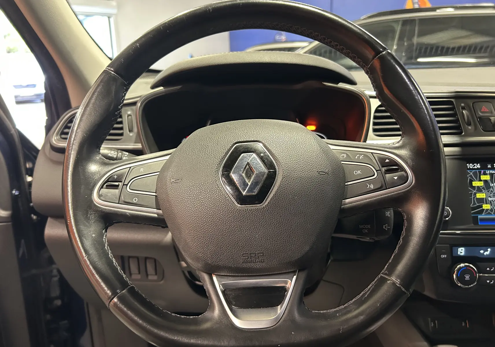 Gros plan sur le volant en cuir noir du Renault Kadjar TCe 130 Intens, avec commandes intégrées et tableau de bord en arrière-plan.