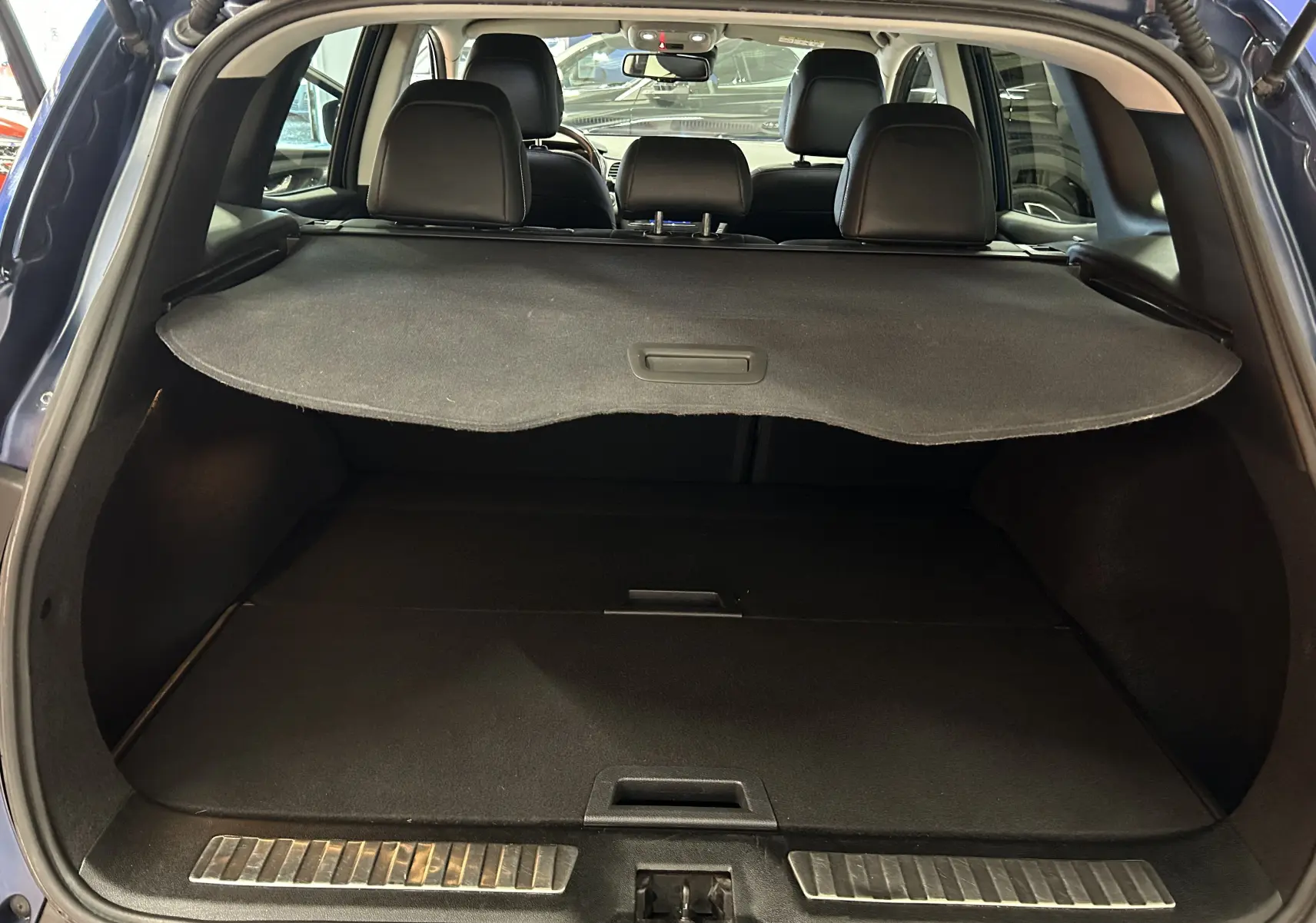 Coffre ouvert d'un Renault Kadjar bleu 2017, montrant la plage arrière et les sièges noirs en arrière-plan.