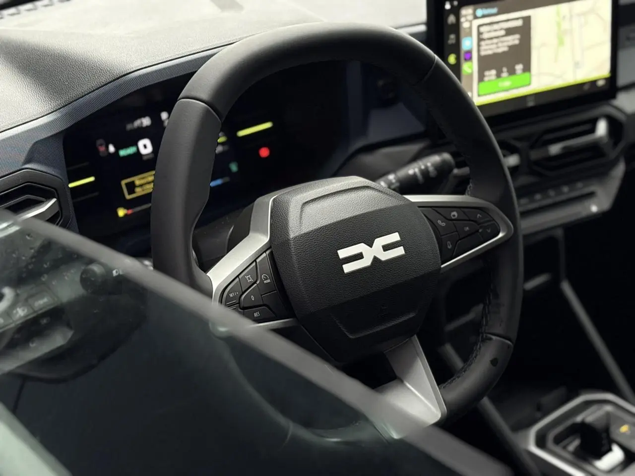 Vue rapprochée du volant noir et du tableau de bord digital du Dacia Duster 1.6 Hybrid 140 Journey 2025.