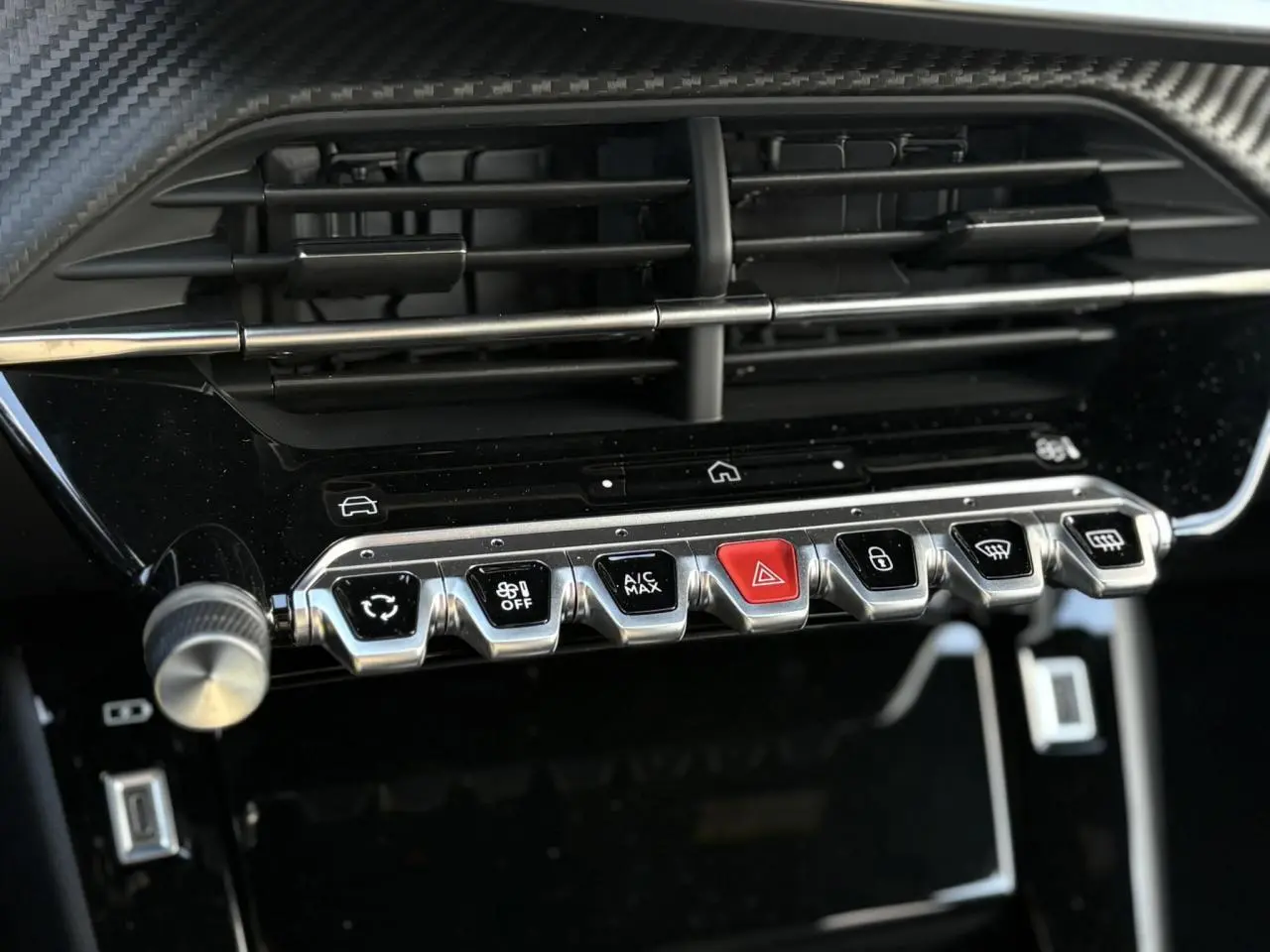 Gros plan sur la console centrale noire du Peugeot 2008 Hybrid 145, montrant les commandes chromées et un bouton rouge d’alerte.