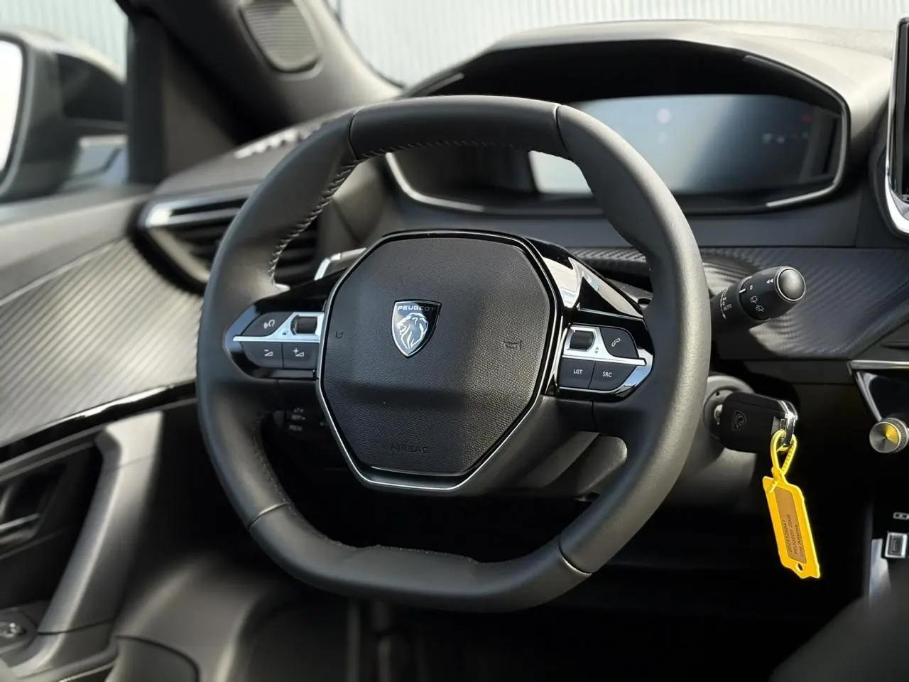 Vue rapprochée du volant compact cuir noir de la Peugeot 2008 Hybrid 145 e-DSC6 Allure avec tableau de bord numérique.