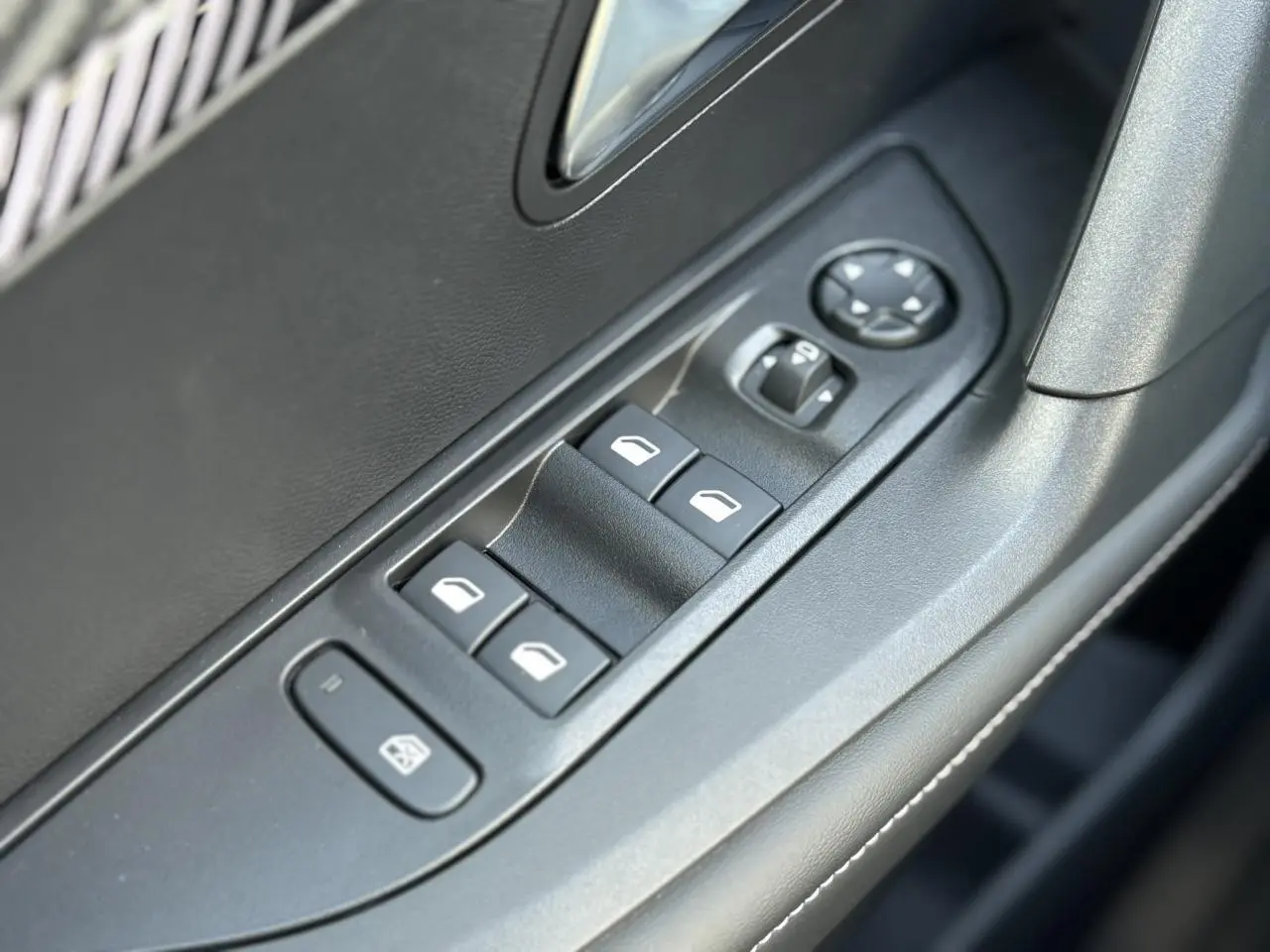 Gros plan sur les commandes des vitres électriques et rétroviseurs côté conducteur du Peugeot 2008 Hybrid gris Artense.