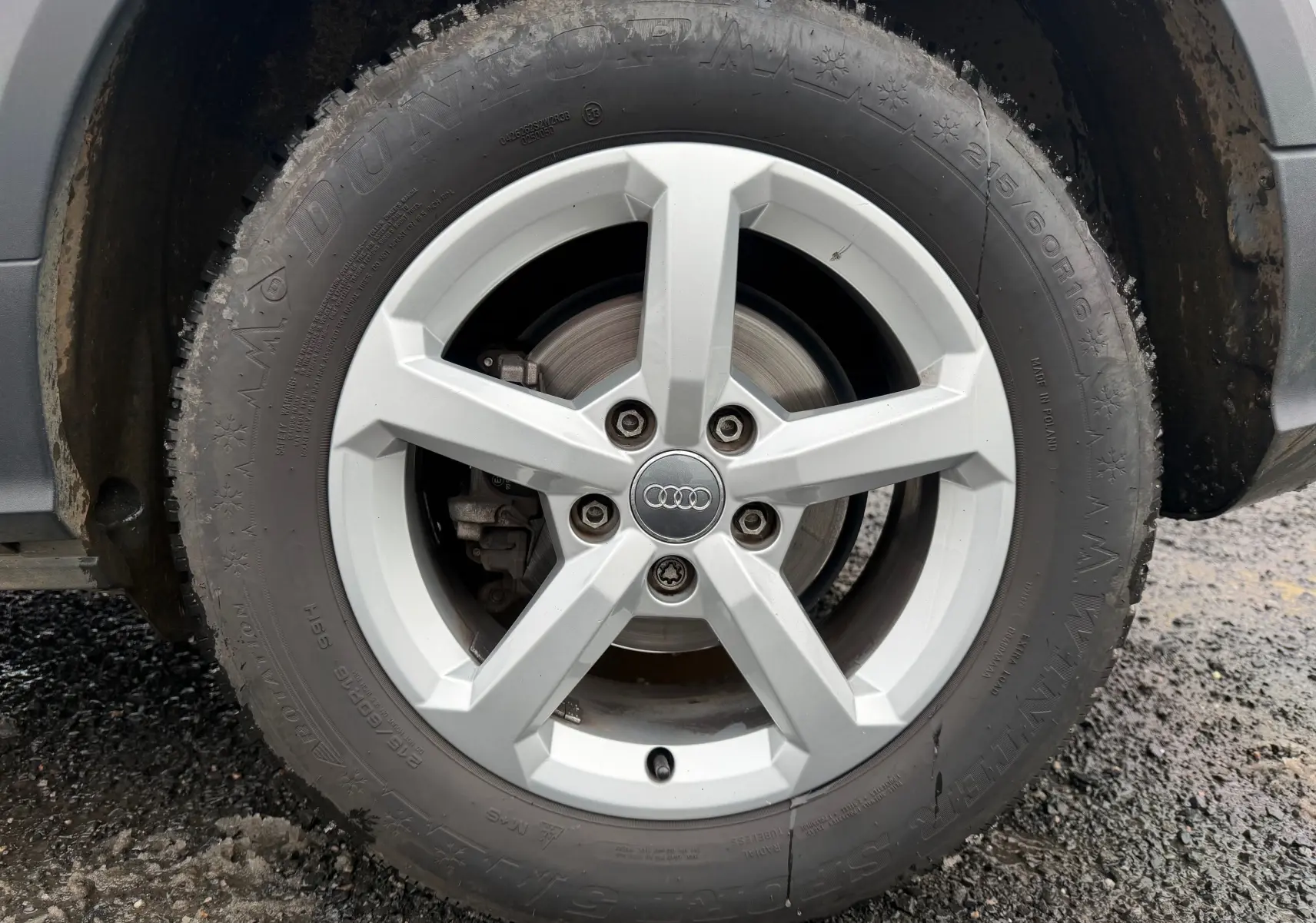 Gros plan sur la roue avant droite d’un Audi Q2 gris aluminium, avec jante alliage 5 branches et logo Audi central.