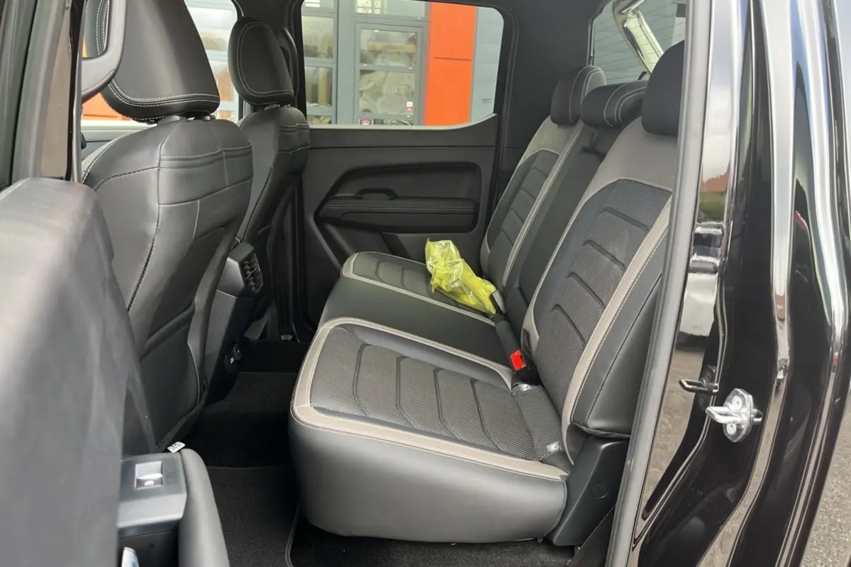 Vue latérale intérieure côté droit du Volkswagen Amarok noir, montrant les sièges arrière en cuir et tissu gris avec surpiqûres claires.