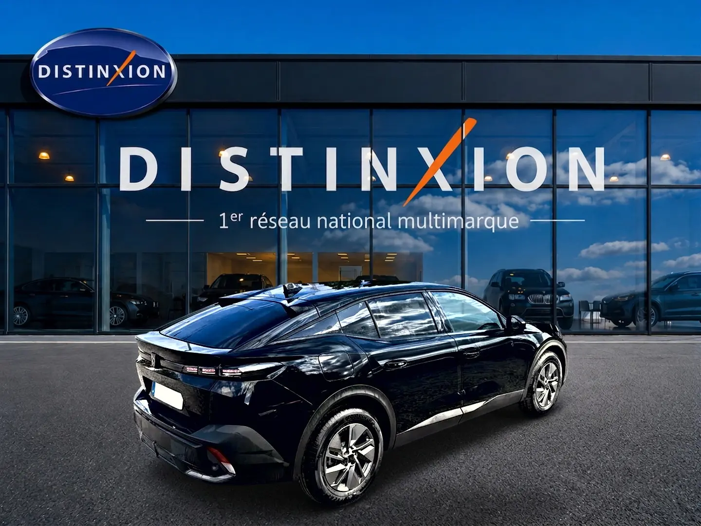 Vue 3/4 arrière droite d'une Peugeot 408 Hybrid 145 allure e-dcs6 noire, avec jantes alu et vitres teintées, devant un showroom Distinxion.