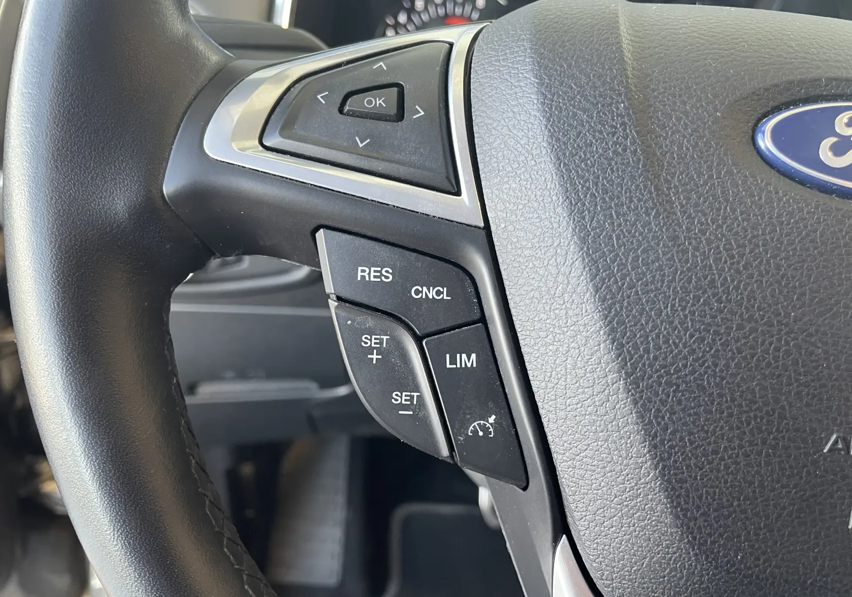 Gros plan sur le côté gauche du volant en cuir noir du Ford S-MAX Vignale gris, avec commandes de régulateur de vitesse visibles.