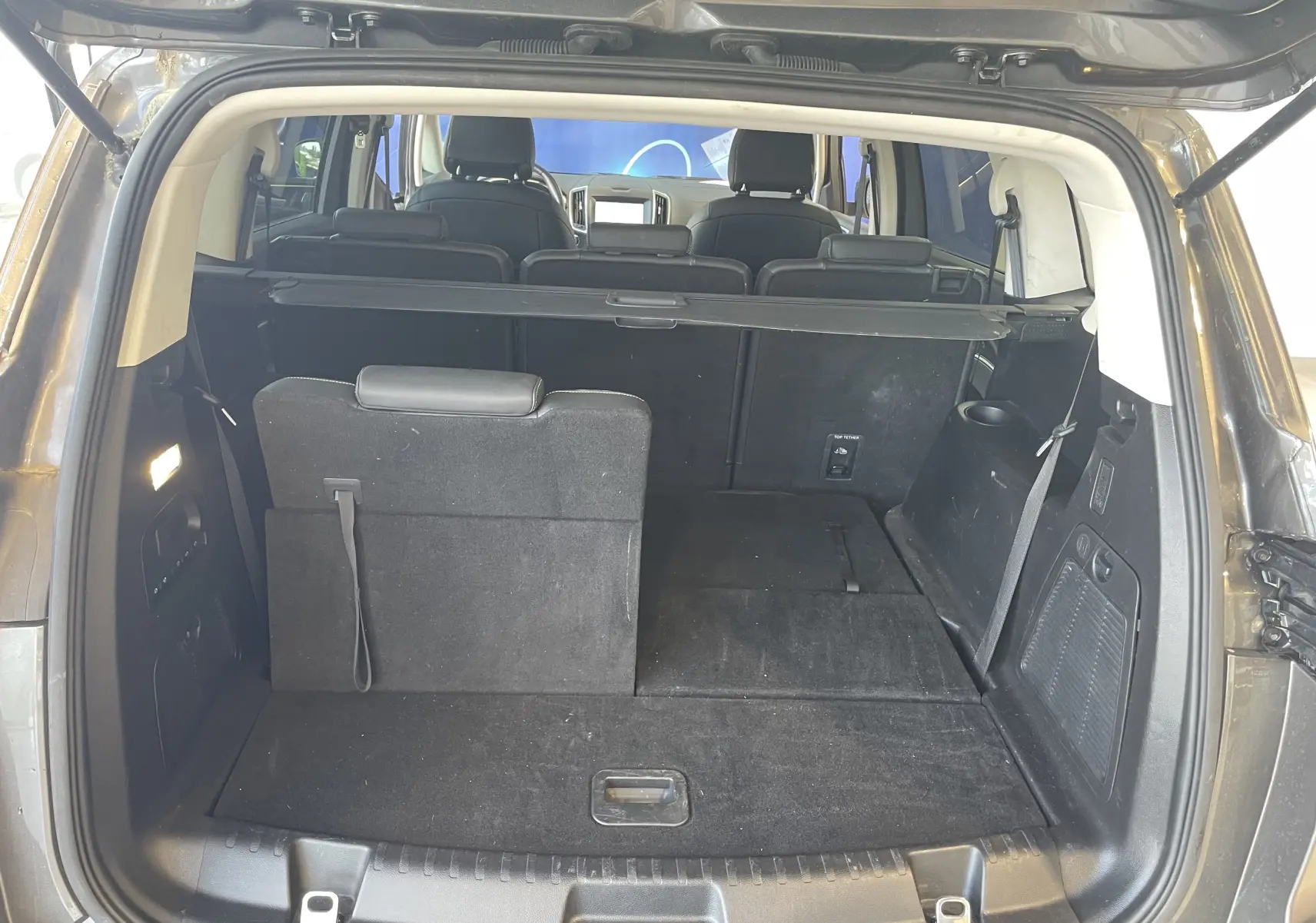 Vue arrière du coffre ouvert du Ford S-MAX Vignale gris magnetic 2022, montrant les sièges arrière partiellement rabattus.