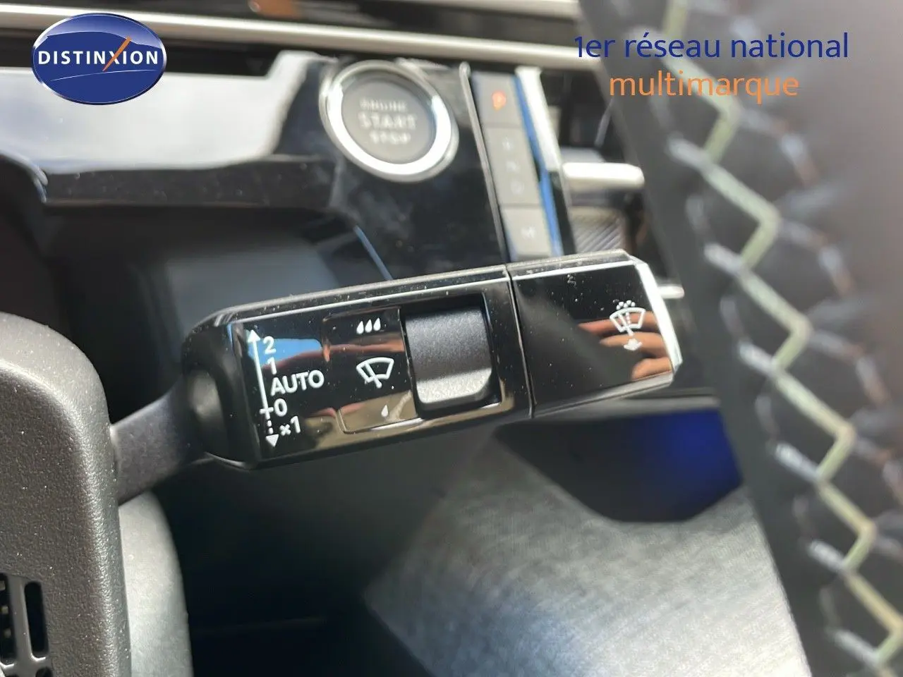 Gros plan sur la commande d'essuie-glace à gauche du volant dans l'habitacle du Peugeot 3008 hybride 2025.