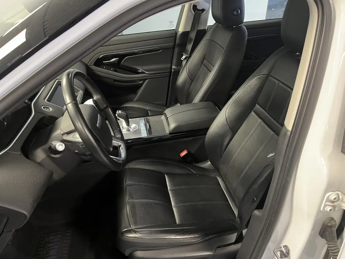 Intérieur côté conducteur du Range Rover Evoque blanc 2020 avec sièges cuir noirs et console centrale élégante.