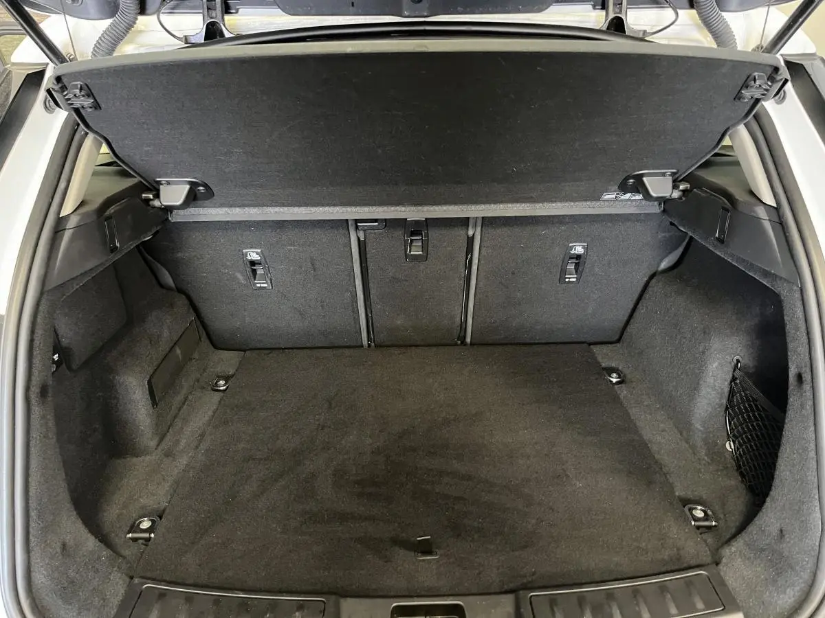 Coffre ouvert du Range Rover Evoque blanc 2020, montrant un espace de chargement propre et bien aménagé.